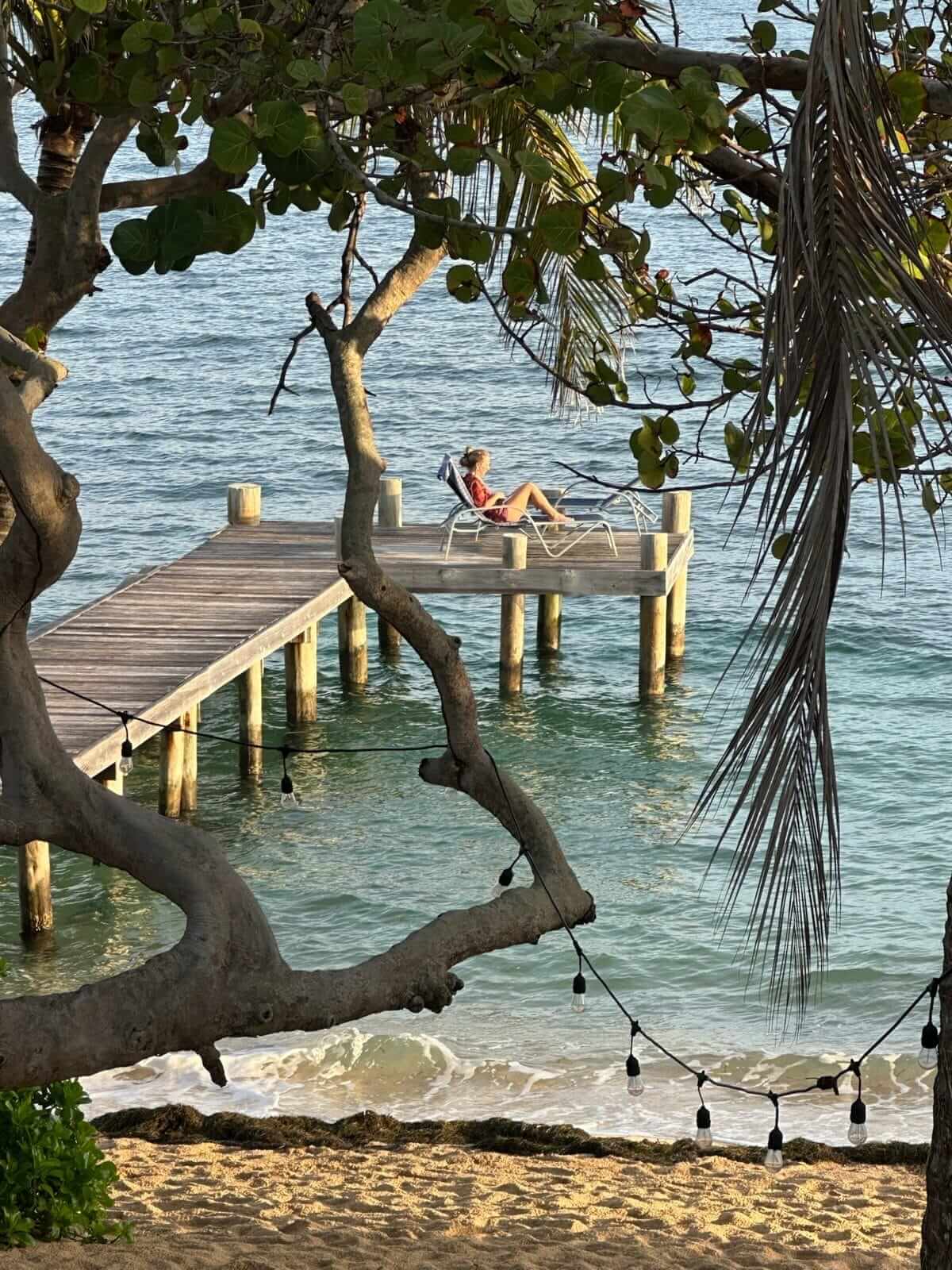 A retreat guest reading alone on a lounger at the end of the dock in golden light