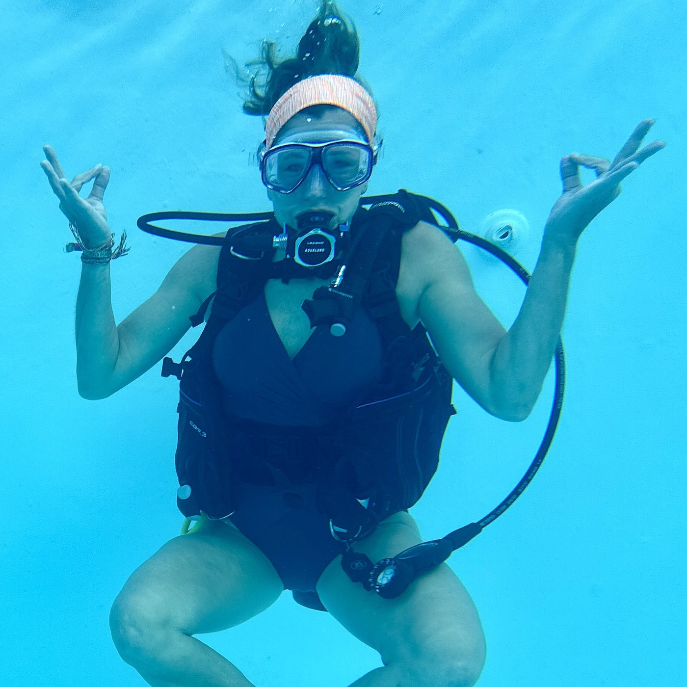 A retreat guest meditating underwater in the pool, seated with her hands in mudra